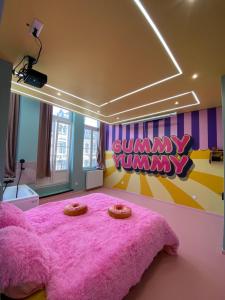 a bedroom with a pink bed with a pink blanket at Capsule Bonbon - Balneo - Sauna - Billard - Nintendo Switch in Douai