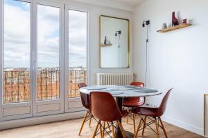 ein Esszimmer mit einem Tisch und Stühlen sowie einem Balkon in der Unterkunft GuestReady - Serene Retreat near Paris in Montrouge