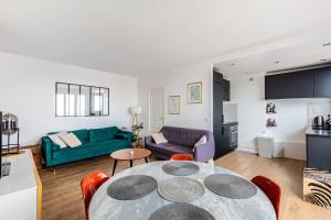 ein Wohnzimmer mit einem Tisch und einem grünen Sofa in der Unterkunft GuestReady - Serene Retreat near Paris in Montrouge