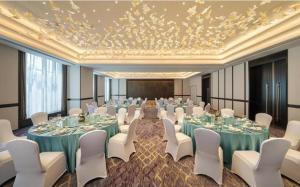 un salón de banquetes con mesas, sillas blancas y una pantalla en Raffles Executive Apartment - Guangzhou Zhengjia Plaza Sports West Road StationBranch -Canton Fair Free Shuttle, en Guangzhou