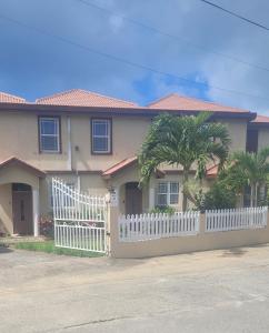 a house with a white picket fence and palm trees at Impeccable Comfortable 1-Bed Apartment in Road Town