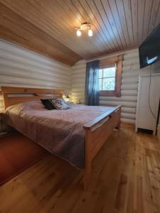 um quarto com uma cama grande num quarto de madeira em Viihtyisä ja tilava mökki, Pytkykaksonen B em Syöte