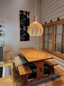 a wooden table and bench in a room with a light at Viihtyisä ja tilava mökki, Pytkykaksonen B in Syöte