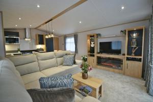 a living room with a couch and a tv at Tranquility at Chantry Lodge in Clitheroe