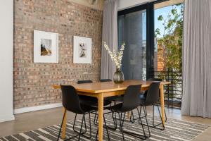 a dining room with a wooden table and black chairs at Neighbourgood Loop Street in Cape Town