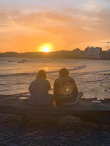埃爾梅達諾的住宿－Los Martines el Medano，两个人坐在长凳上看日落
