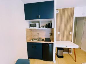 a small kitchen with blue cabinets and a microwave at Studio entre Disney & Paris proche lacs in Torcy