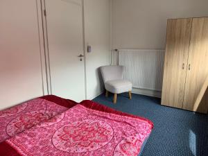 - une chambre avec une couverture rose sur un lit et une chaise dans l'établissement Haus Michel, à Bad Wildungen