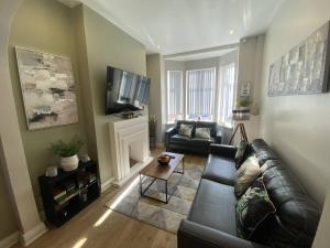 a living room with a leather couch and a tv at 2br Cozy Duplex in Belfast