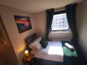 um pequeno quarto com uma cama e uma janela em 2br Spacious City Centre Apartment em Belfast