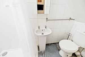 a white bathroom with a toilet and a sink at Cosy Tottenham Apartment sleeps 4 in London