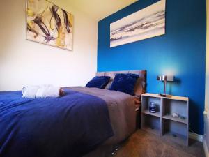 um quarto com uma cama e uma parede azul em 3br Cosy Modern Stay em Belfast