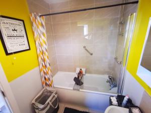 a small bathroom with a tub and a shower at 3br Cosy Modern Stay in Belfast