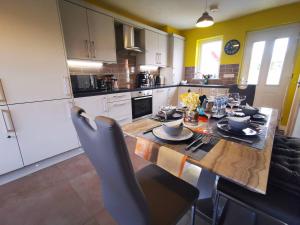 a kitchen with a wooden table with chairs and a dining room at 3br Cosy Modern Stay in Belfast