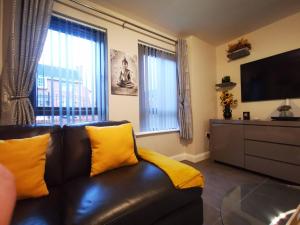 a living room with a brown leather couch with yellow pillows at Belfast Central 2 Bedroom Luxurious Modern Stay in Belfast