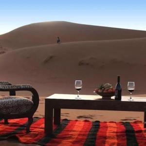 a table with two glasses of wine in the desert at Hostel Desert camp Sam in Jaisalmer