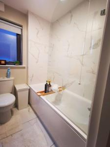 a white bathroom with a tub and a toilet at Belfast Central 2 Bedroom Luxurious Modern Stay in Belfast