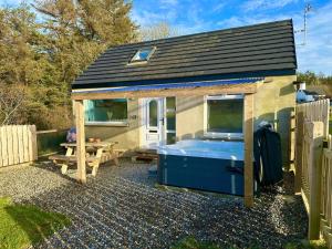 a small shed with a hot tub and a picnic table at Forest View Cottage - Private Hot Tub in Ballynameen