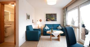 uma sala de estar com cadeiras azuis e uma mesa em Försterhäusl em Seefeld in Tirol