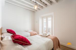 two beds in a white room with red pillows at Buenos Aires by Cadiz Time in Cádiz