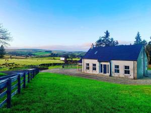 une petite maison dans un champ avec une clôture dans l'établissement Forest View House & Hot Tub Sleeps 9, à Ballynameen