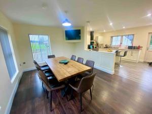 a dining room and kitchen with a wooden table and chairs at Forest View House & Hot Tub Sleeps 9 in Ballynameen