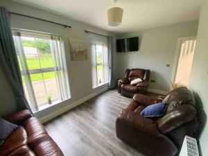 a living room with two leather chairs and a couch at Forest View House & Hot Tub Sleeps 9 in Ballynameen