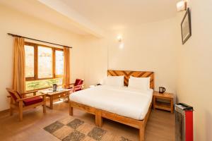 a bedroom with a bed and a desk and a window at Prakriti-The Retreat in Gangotri