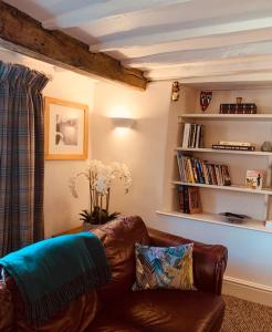a living room with a couch and a book shelf at Exmoor, Devon - charming cottage , characterful and brimming with Hygge! in Tiverton