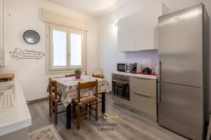 eine Küche mit einem Tisch und einem Kühlschrank aus Edelstahl in der Unterkunft Casa Laura comodissima al centro e spiagge in Diano Marina
