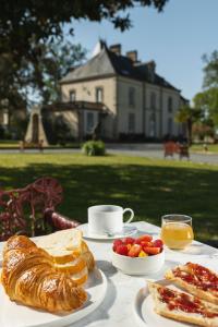 una mesa con bollería, fruta y una taza de café en CHATEAU DE LA RICHERIE, en Beaurepaire