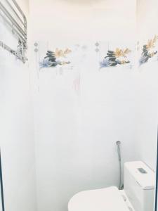 biała łazienka z toaletą i kwiatami na ścianie w obiekcie KimMy Home w mieście Phan Thiet