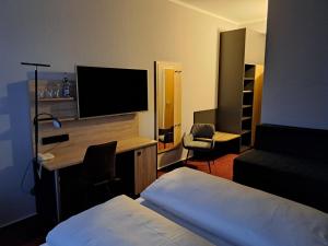a hotel room with a bed and a desk with a television at Best Western Comfort Business Hotel Düsseldorf-Neuss in Neuss
