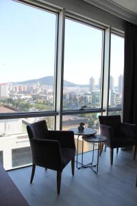 イスタンブールにあるVplus hotel atasehirの椅子とテーブル、大きな窓が備わる客室です。