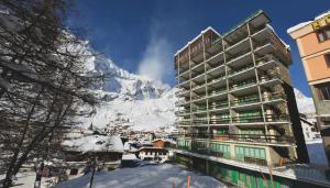 a hotel with a snow covered mountain in the background at Mollino Rooms by Skilink (Winter) in Breuil-Cervinia