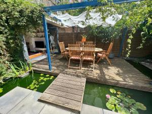 eine Terrasse mit einem Tisch, Stühlen und einem Teich in der Unterkunft Urban Oasis Chic 1BR Flat with Spacious Garden in London