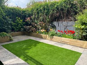 un jardin avec de l'herbe verte et des fleurs et une haie dans l'établissement Urban Oasis Chic 1BR Flat with Spacious Garden, à Londres