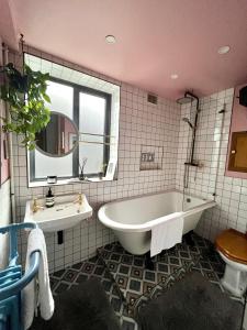 La salle de bains est pourvue d'une baignoire, d'un lavabo et d'un miroir. dans l'établissement Urban Oasis Chic 1BR Flat with Spacious Garden, à Londres