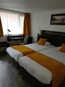 una camera d'albergo con 2 letti e una scrivania di Kyriad Lille Est - Hem a Hem