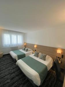 Una habitación de hotel con dos camas y dos lámparas. en Hotel du Louvre, en Cherbourg-en-Cotentin