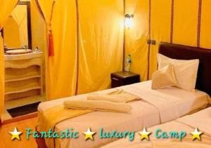 a bedroom with two beds with yellow walls at Fantastic Luxury Camp in Merzouga