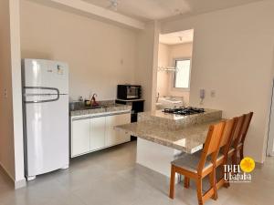 a kitchen with a white refrigerator and a counter top at Thel Ubatuba - Apto 35/A, Ibiza - Praia Grande in Ubatuba