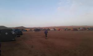 mężczyzna spacerujący po pustyni z grupą namiotów w obiekcie Auberge Dinosaur Kem Kem w mieście Tafraoute Sidi Ali