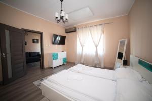- une chambre avec un grand lit blanc et une fenêtre dans l'établissement Milan house, à Arad