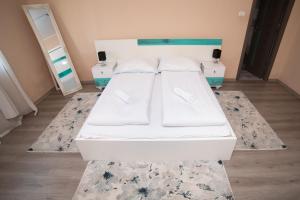 un letto bianco in una camera con due cuscini di Milan house a Arad
