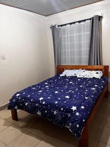 a bed with a blue blanket with stars on it at Klimax Homes in Kiambu