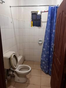 a bathroom with a toilet and a blue shower curtain at Klimax Homes in Kiambu