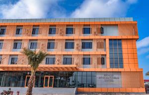 ジブチにあるEscale International Hotelのヤシの木が目の前に広がるオレンジ色の建物