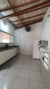 a large kitchen with white walls and a wooden ceiling at Quintal da Canastra - Room in São João Batista do Glória