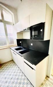 ゲッピンゲンにあるExklusive Wohnung im Herzen von Göppingenの白いキャビネットと黒い電子レンジ付きのキッチンが備わります。